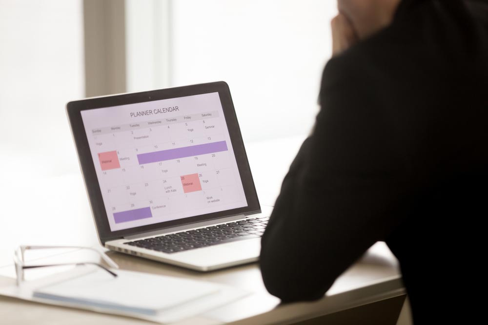 Back over shoulder view of businessman sitting at desk in front of laptop
