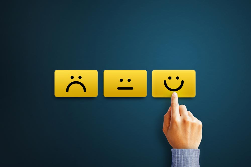 Hand of client show a feedback with smiley face card. Service rating, satisfaction concept