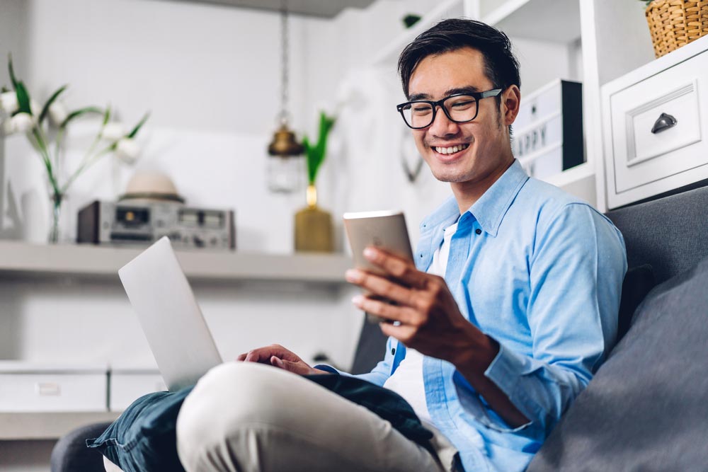 Young smiling asian man relaxing using laptop computer working and video conference meeting at home
