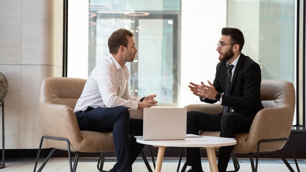 businessmen seated on armchair in modern office talking
