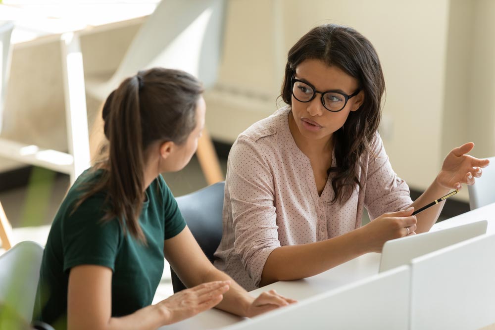 businesswoman talking with female leader in boardroom at meeting
